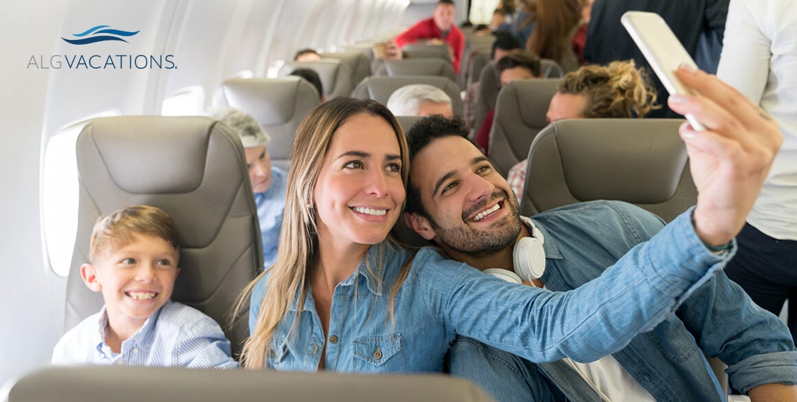 A couple with a child take a selfie on their phone while sitting in an airplane