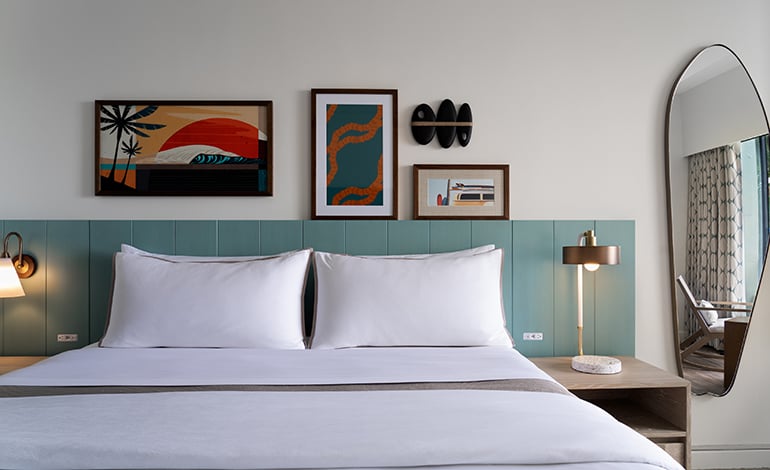 Turquoise headboard with orange-leading artwork over it