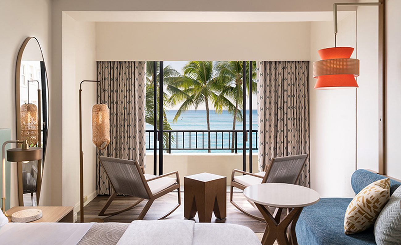 Two rocking chairs in a hotel room facing ocean view balcony