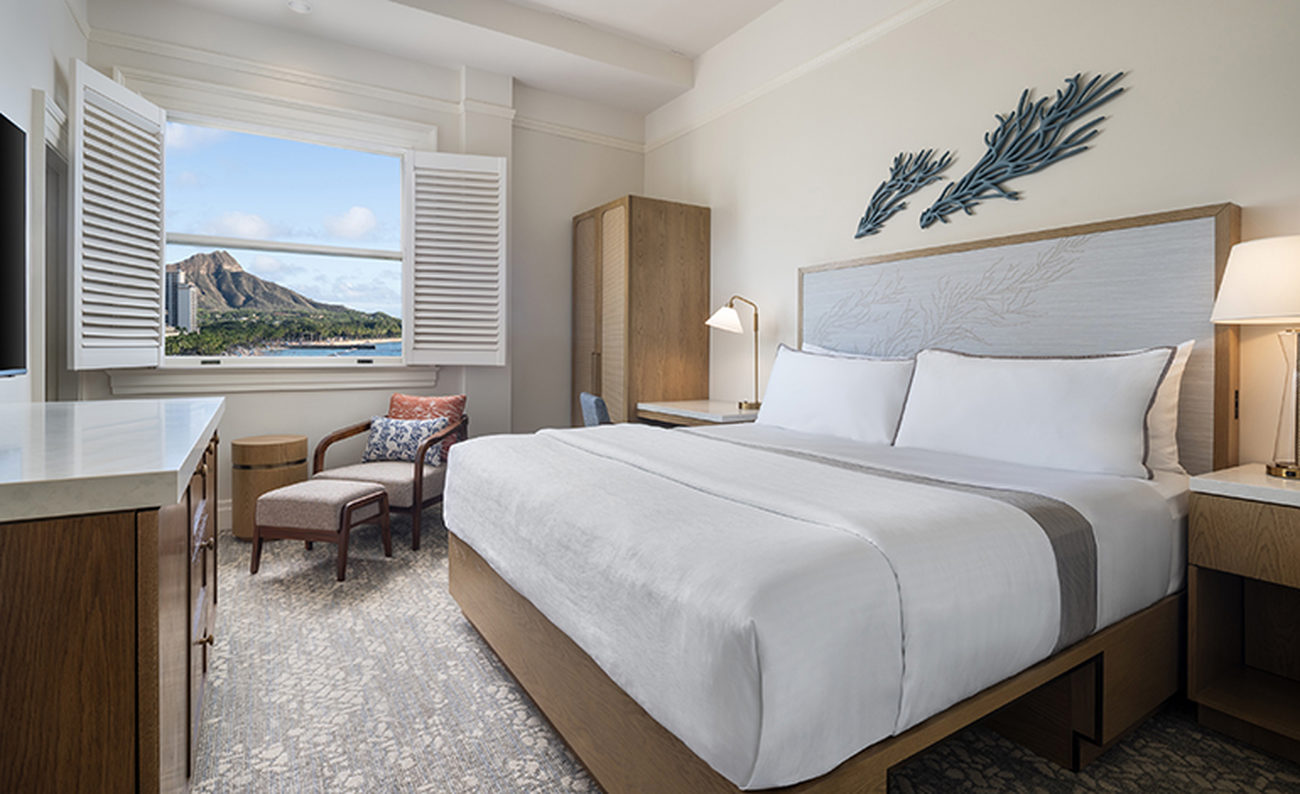 Large bed in a hotel room with a picture window framing a mountain