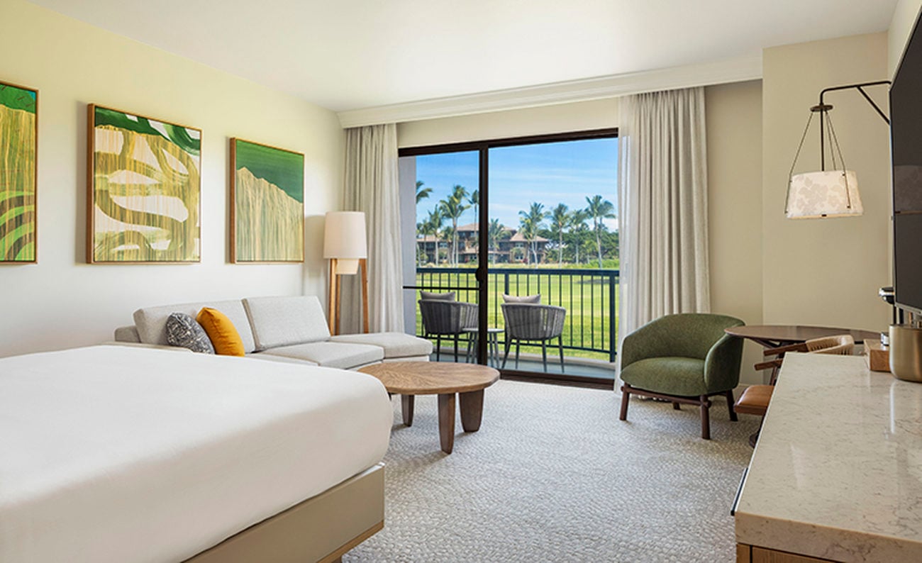 Hotel room with sofa and green artwork facing a lawn