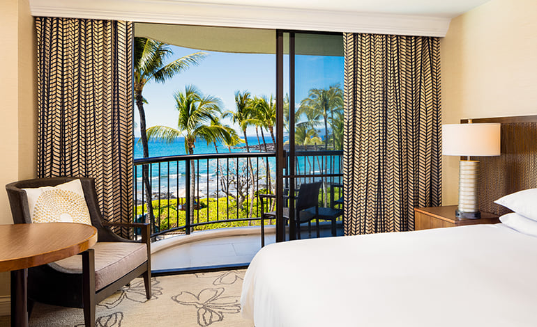 Corner of a bed in a hotel room with ocean views