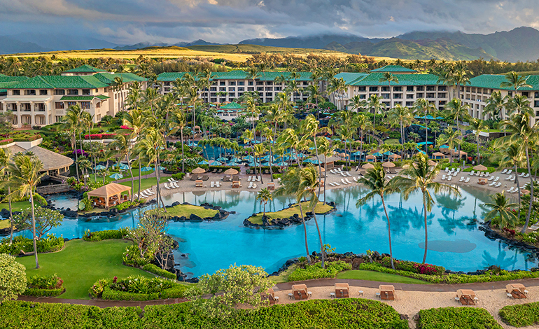 Sunrise over a green-roofed resort overlooking a large pool
