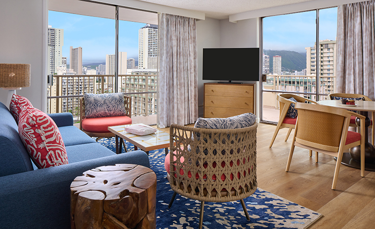 Bright modern hotel room with navy and coral color scheme with floor to ceiling windows with city views