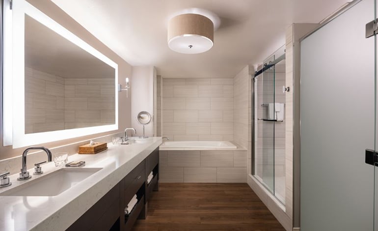Hotel bathroom with double sinks, a tub, and shower