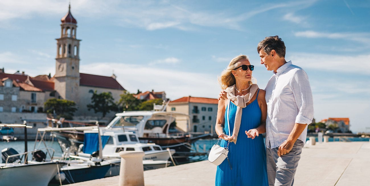 A mature white couple walk along a river canal in Europe