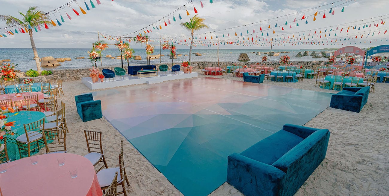 Multi-color dance floor on a beach with velvet couches and pastel tables