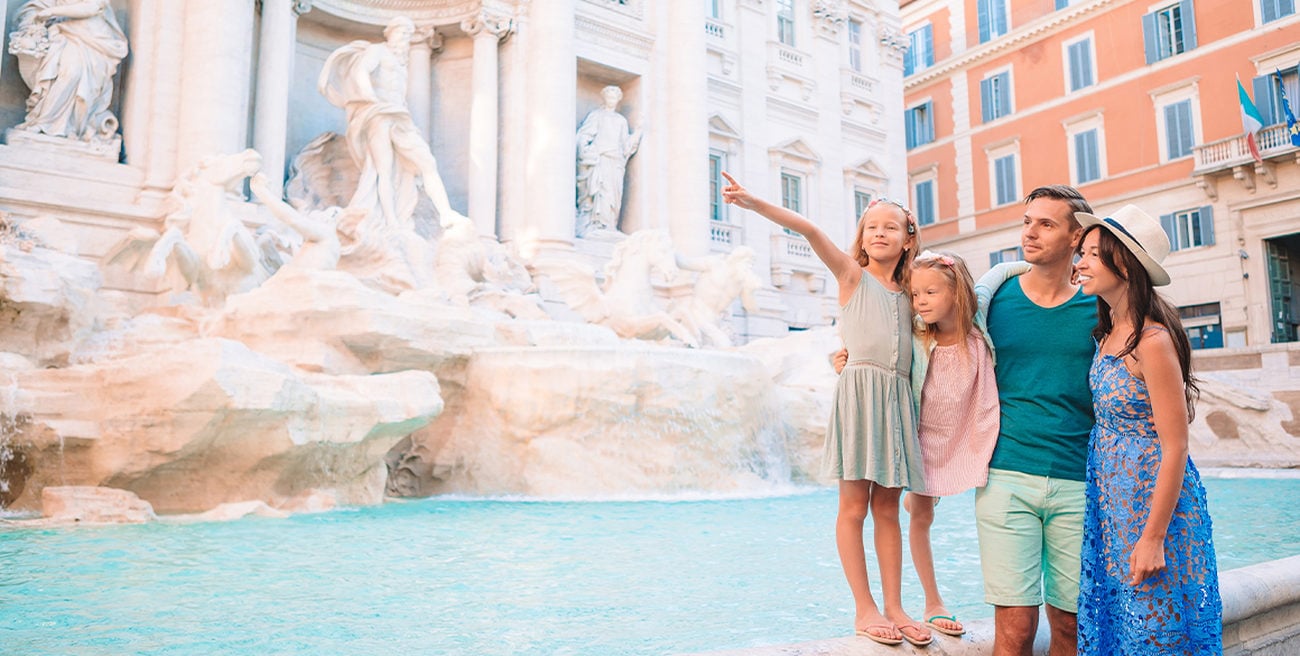A man, woman, and two female children stand on the Trevi Fountain