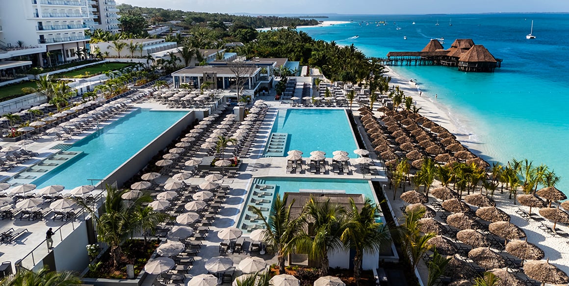 Aerial view of a large beachfront resort and its three pools