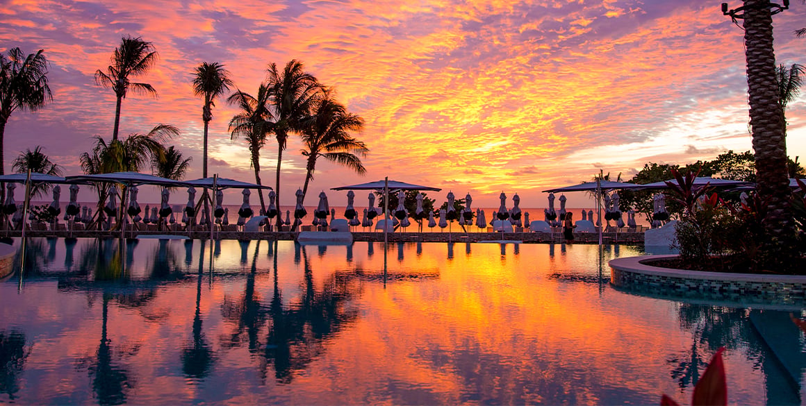 Fiery orange and pink sunset over a resort pool