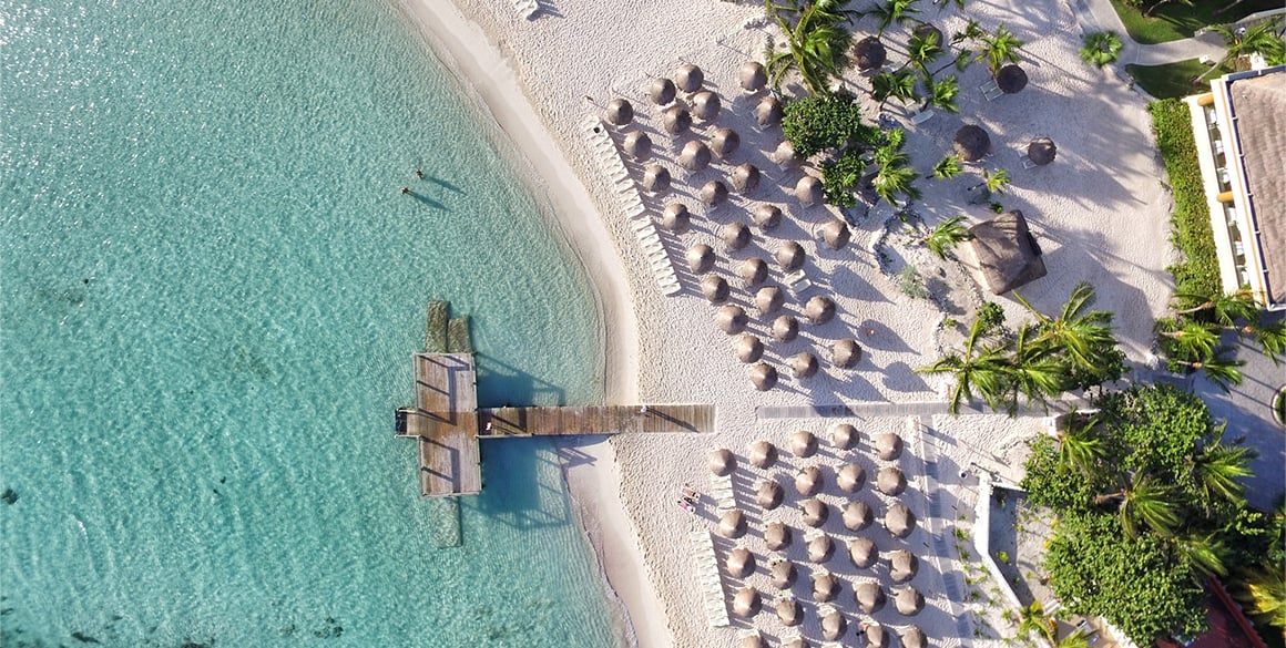 Aerial overhead view of a beach with lounge chairs and clear seas