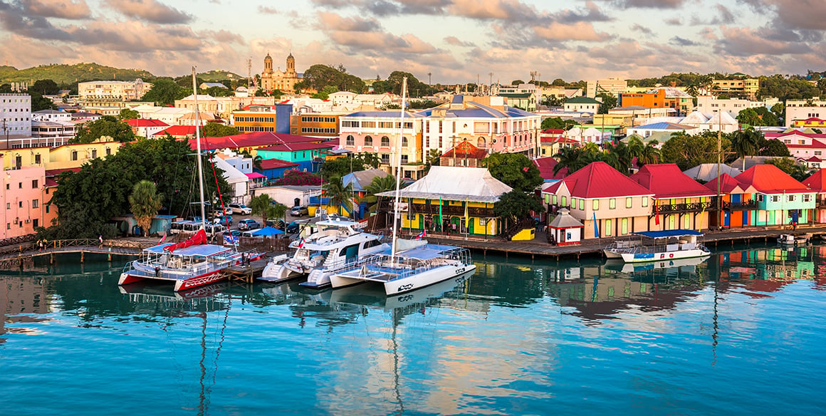 Colorful waterfront buildings and boats along the harbor in St. John’s, Antigua.