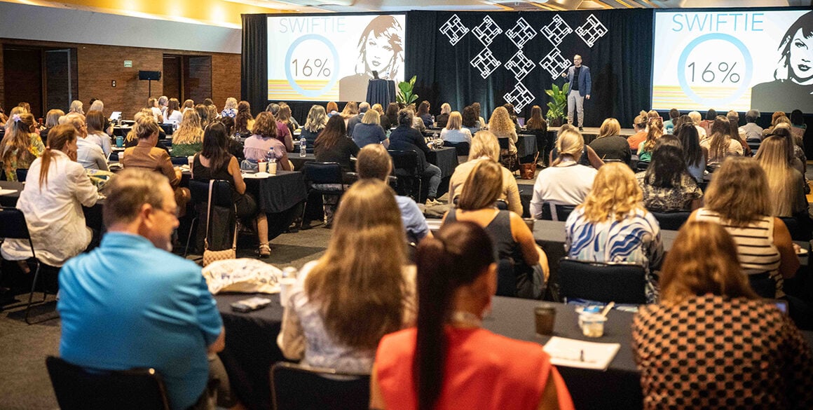 View from the back of a full conference room toward a workshop stage