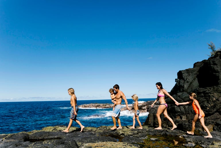 Adults and children walking on a beach in Hawaii