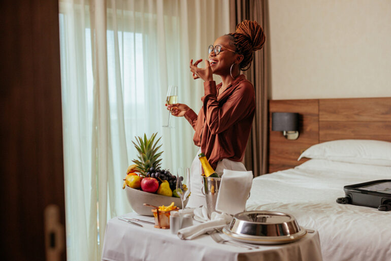 Woman enjoying welcome fruit basket and sparkling wine in hotel