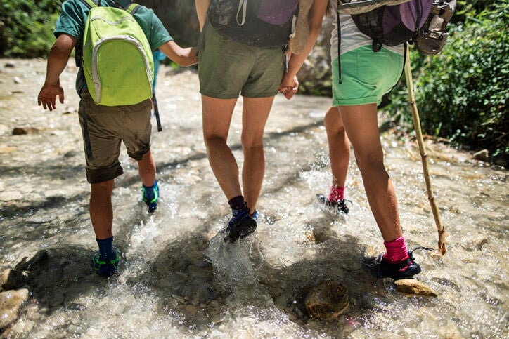 Three children walking on a wet hiking trail