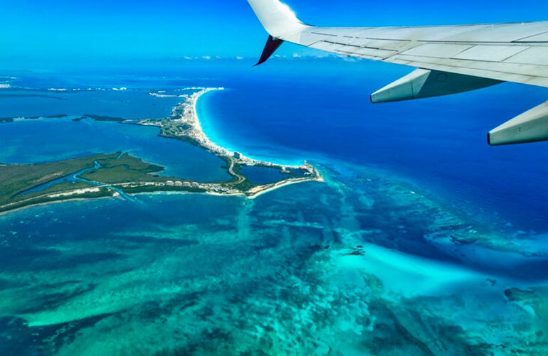 Airplane wing over views of the Cancun Hotel Zone