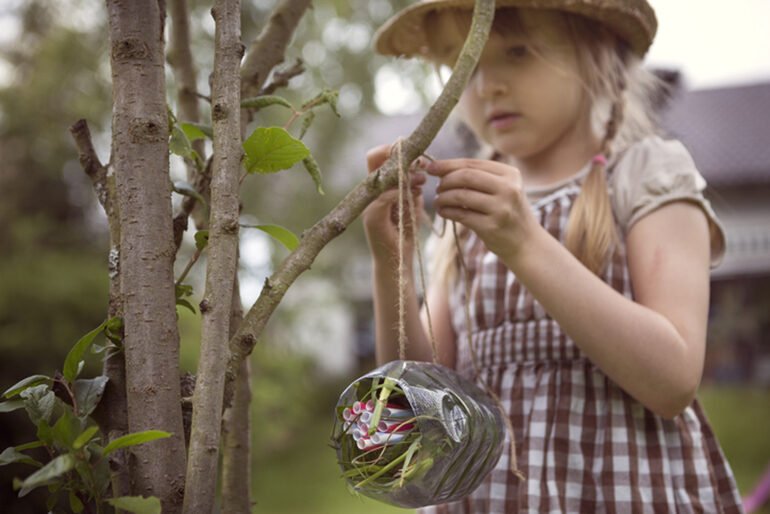 Blonde child with a plastic water bottle that has been repurposed into a hanging planter