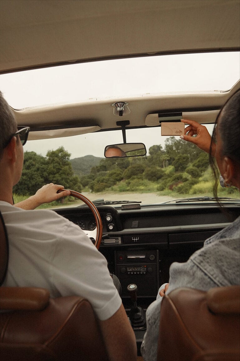 Back view of two people driving a vintage car