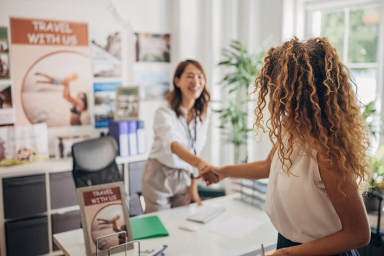 Female travel agent shaking hands with a multi-ethnic woman