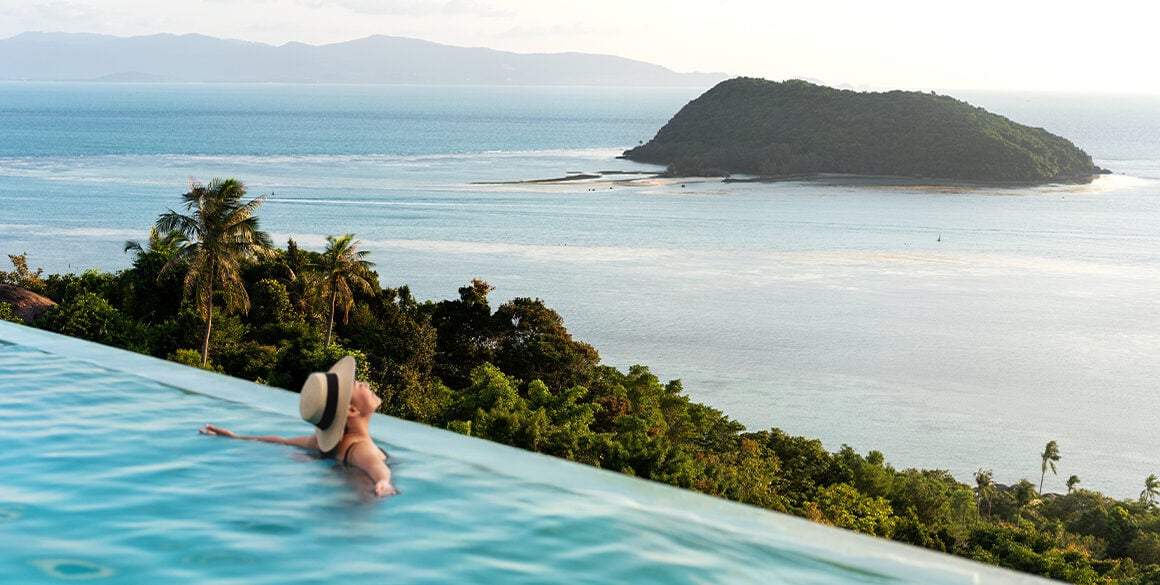 Woman in rooftop pool overlooking an island