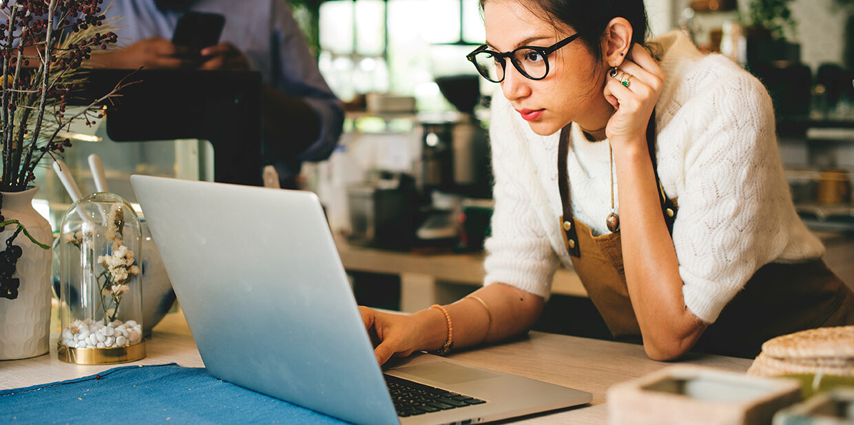 Woman in a coffee shop working intently on her laptop