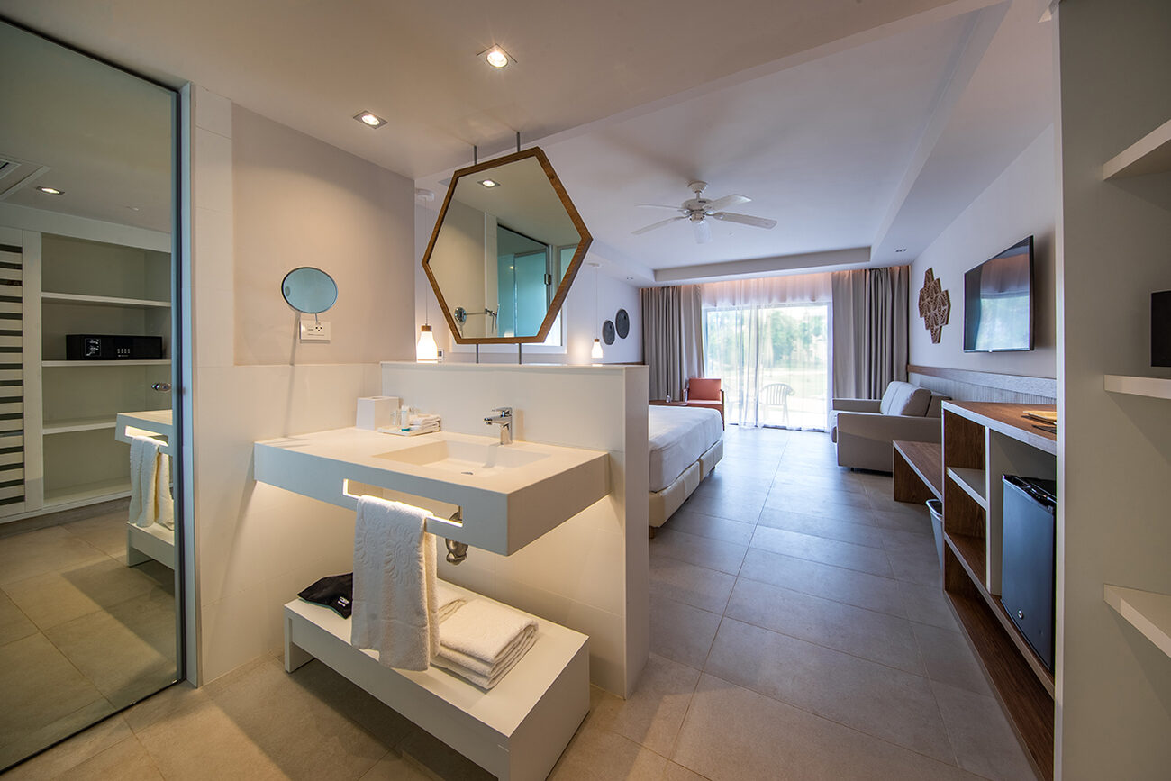 Open concept hotel room with bathroom sink and bedroom