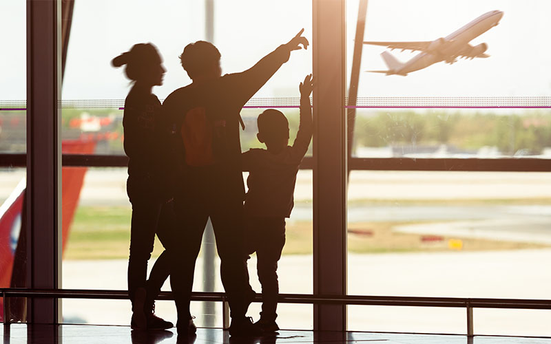 Outline of people waving at a plane taking off out the window