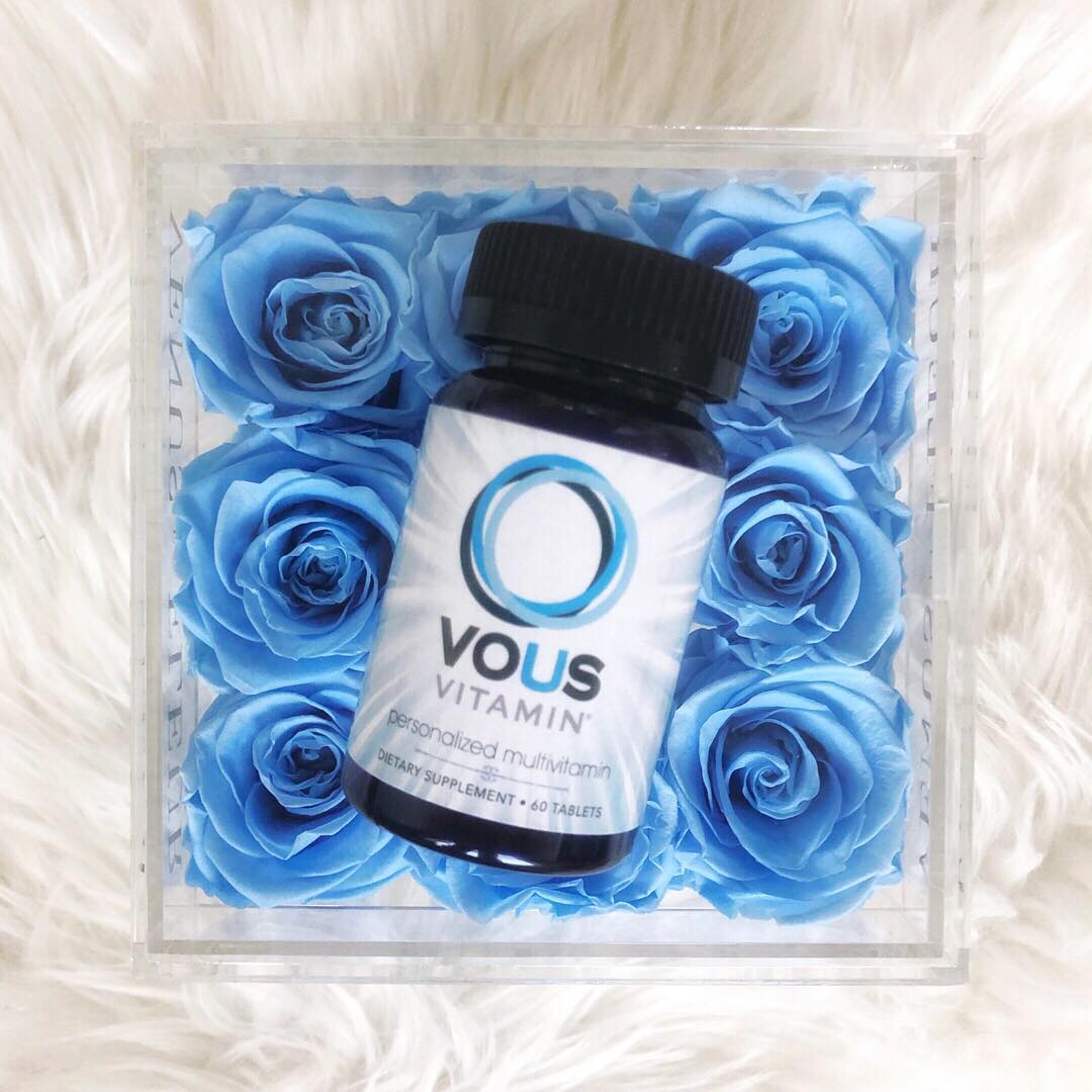 Bottle of Vous vitamins laying on blue flowers