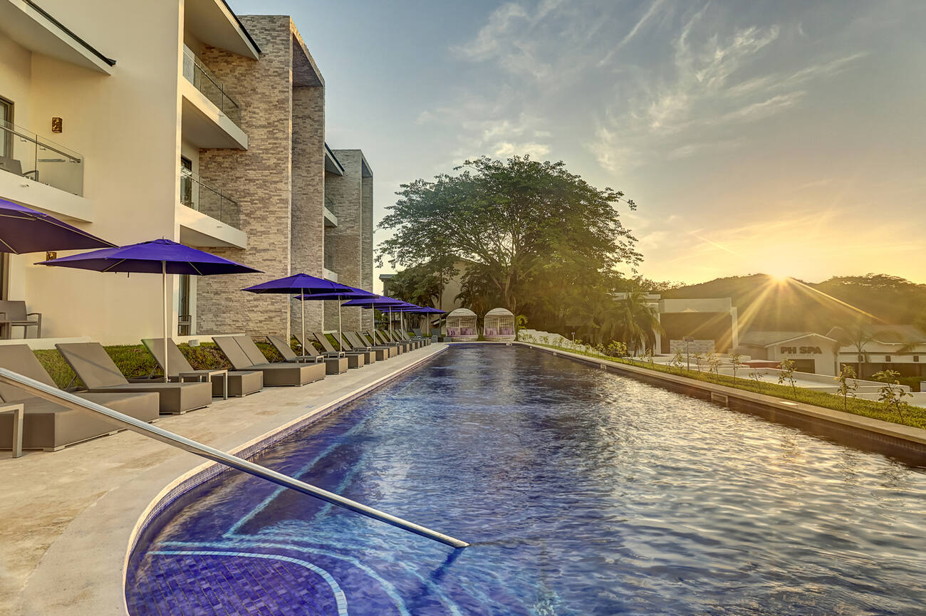 View of pool and lounge chairs at sunset