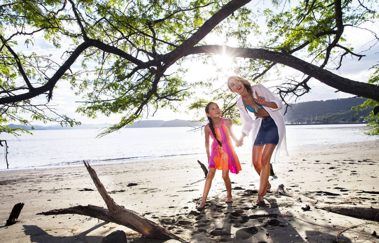 Mother and daughter holding hands and exploring the beach