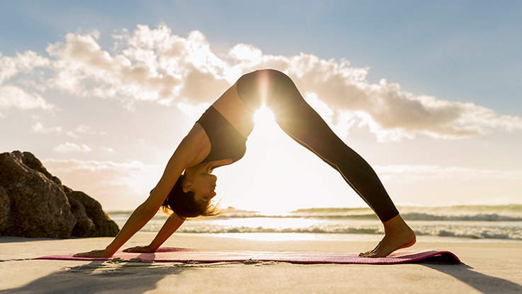 Woman doing yoga on the beach