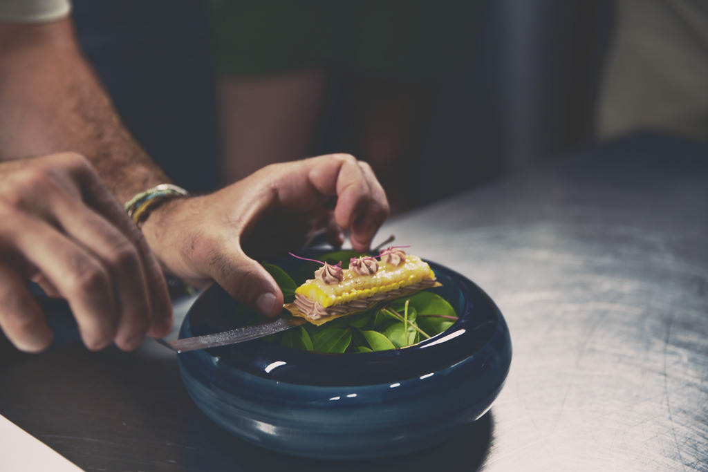 Hands creating a dish of French-influenced cuisine