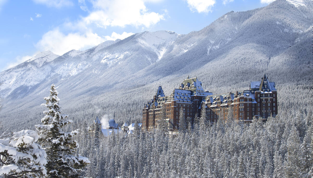 Mountains of snowy trees with a building in the middle