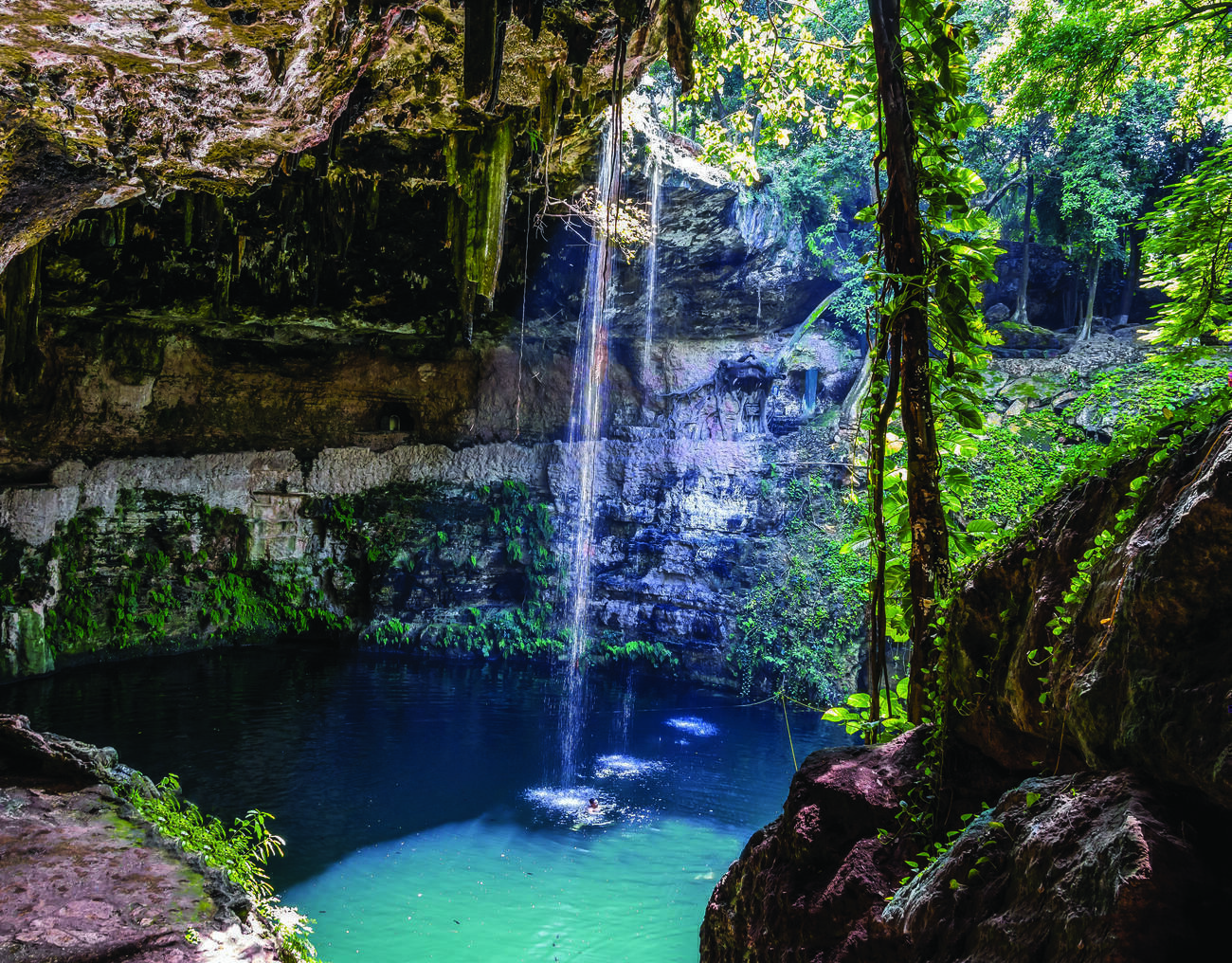 A man swimming in a natural cenote in Yucatan, Mexico.