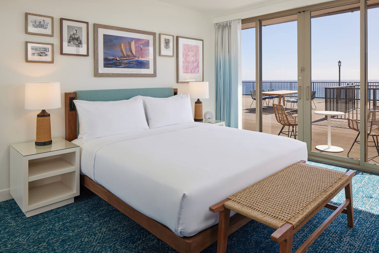 Hotel bed with seating on deck overlooking the ocean