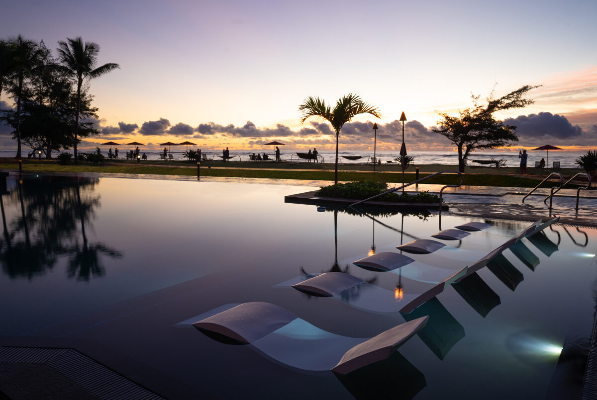 Pool area with lounge chairs in the water overlooking the ocean