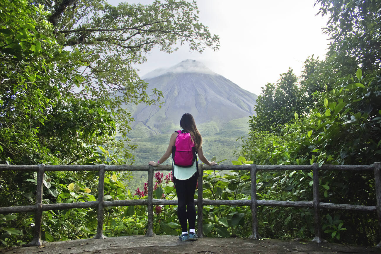 A woman gazes out at Arenal Volcano from an observation point.