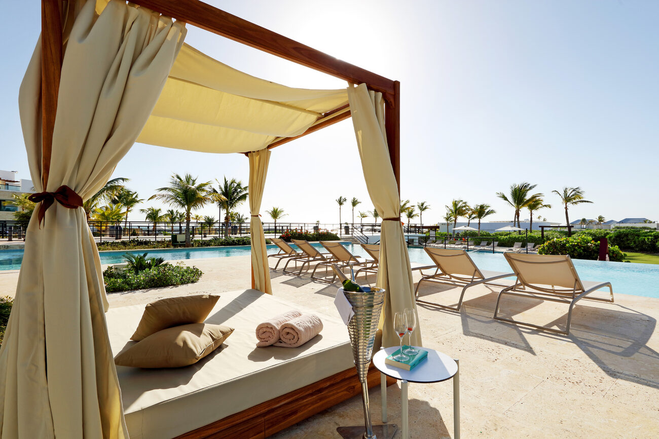 A poolside cabana with chilled Champagne next to a table with two empty glasses on top of a book.