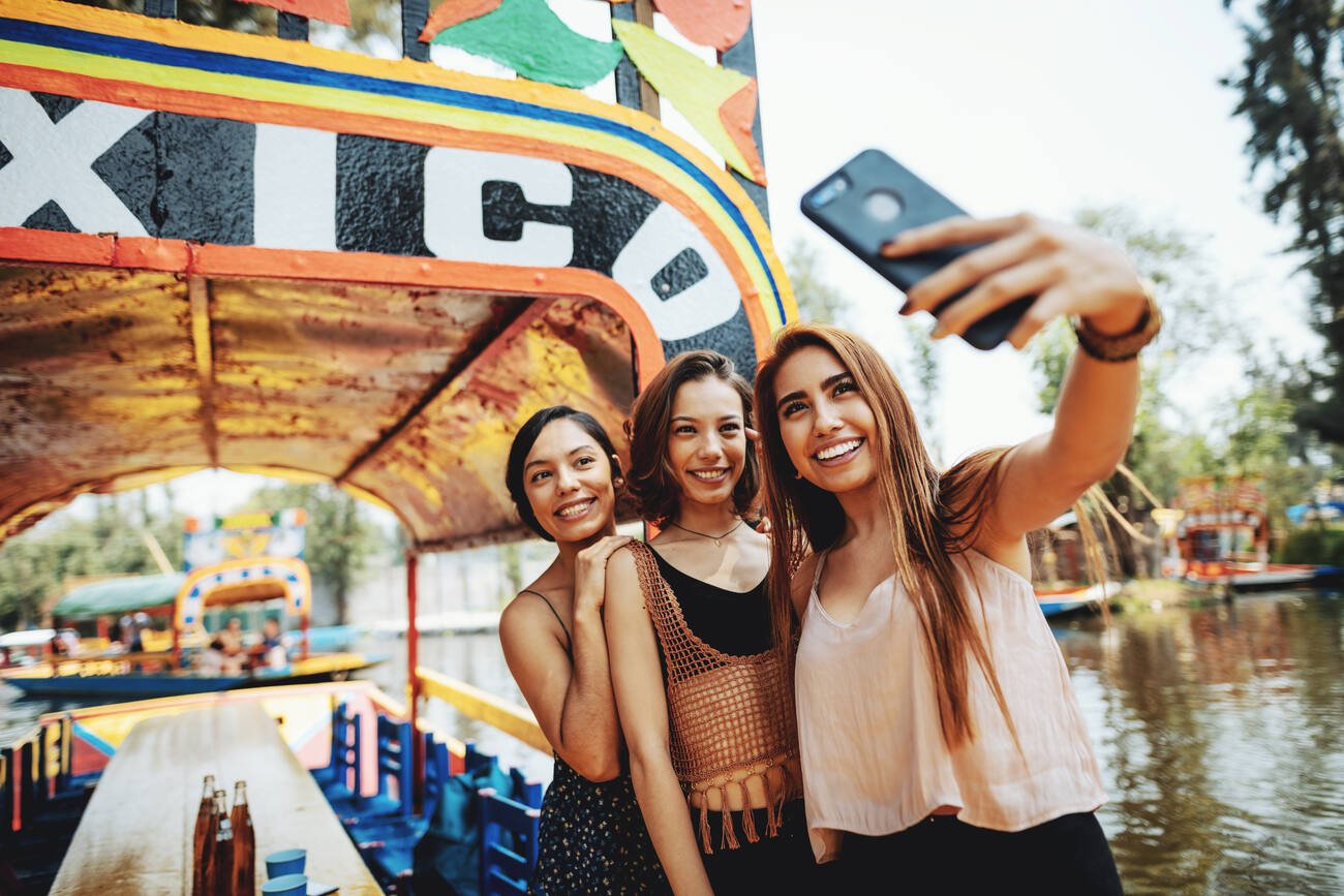 Three young women taking a selfie on a trajinera in Xochimilco.