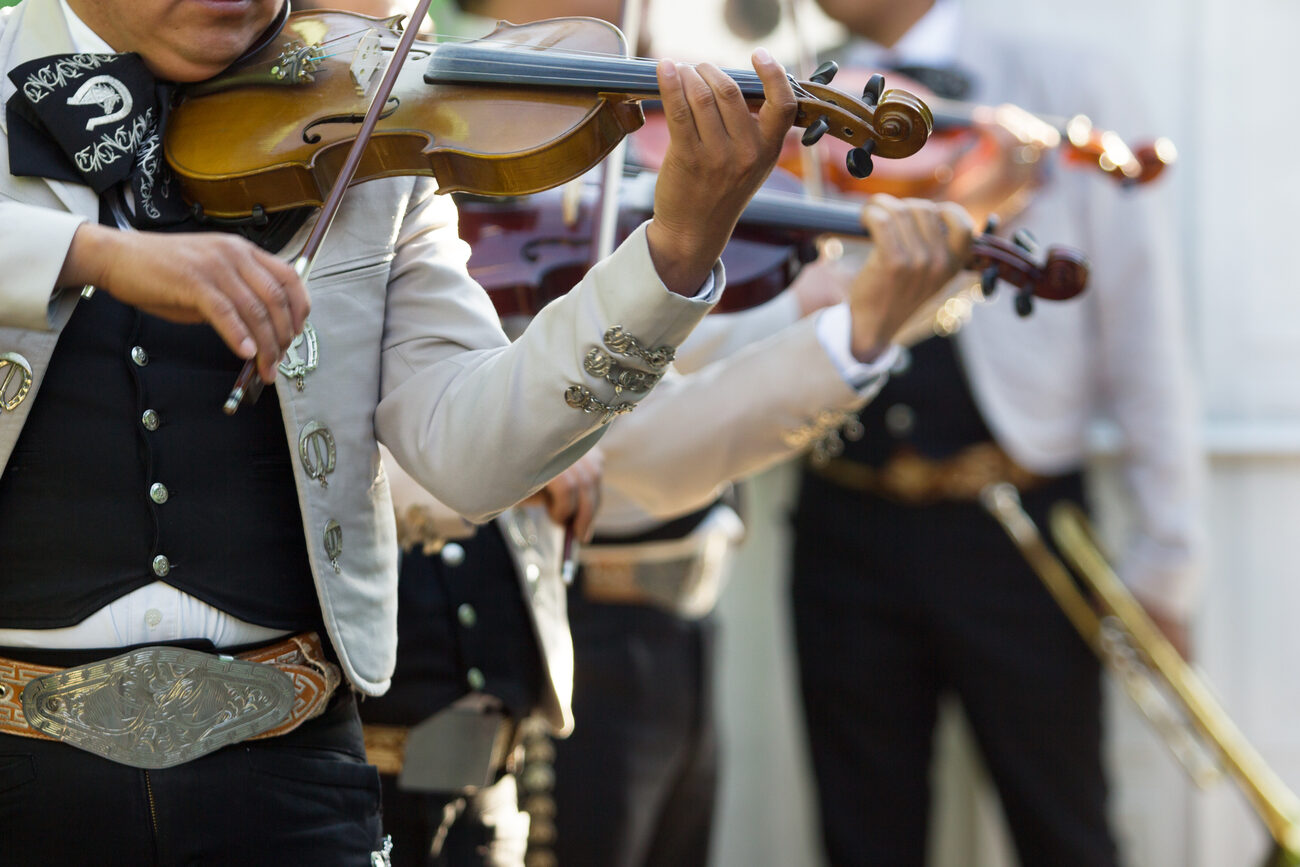 Two members of a mariachi band playing the violin