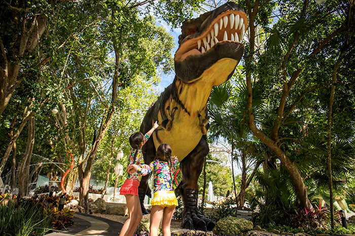 Two girls looking at a dinosaur statue