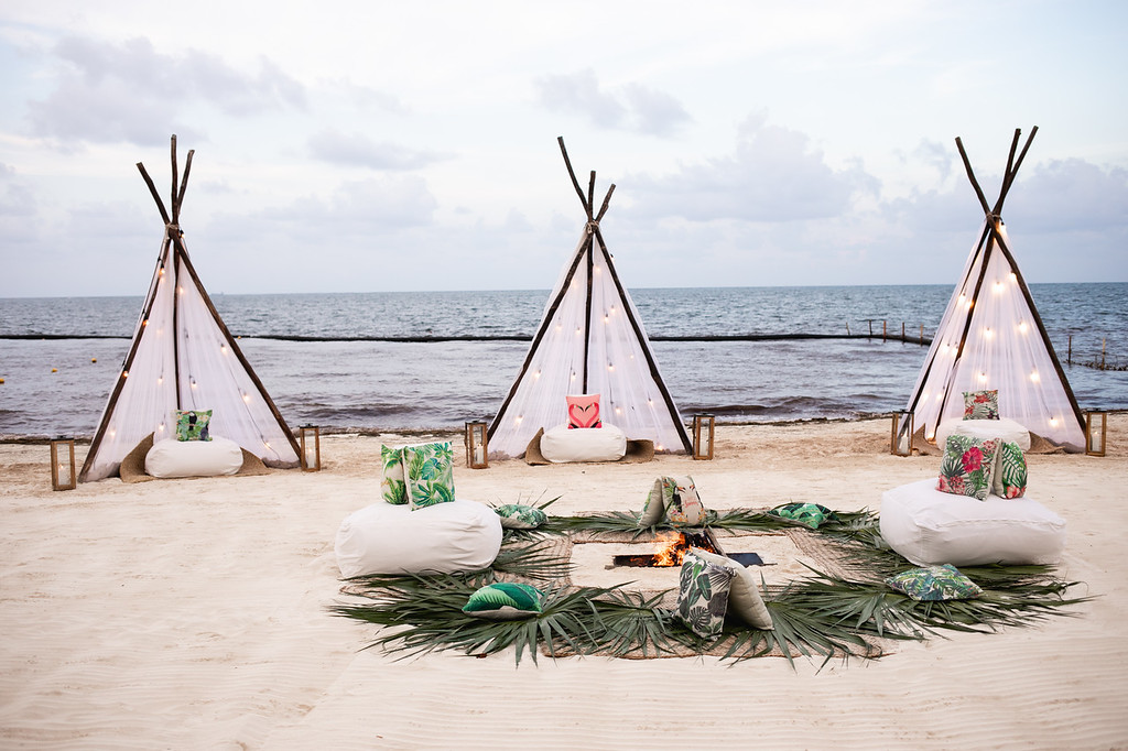 Campfire and lit up teepees on the beach