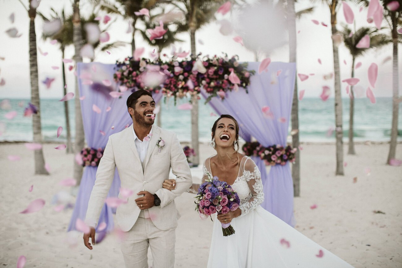 Bride and groom walking down the aisle with flower petals in the air