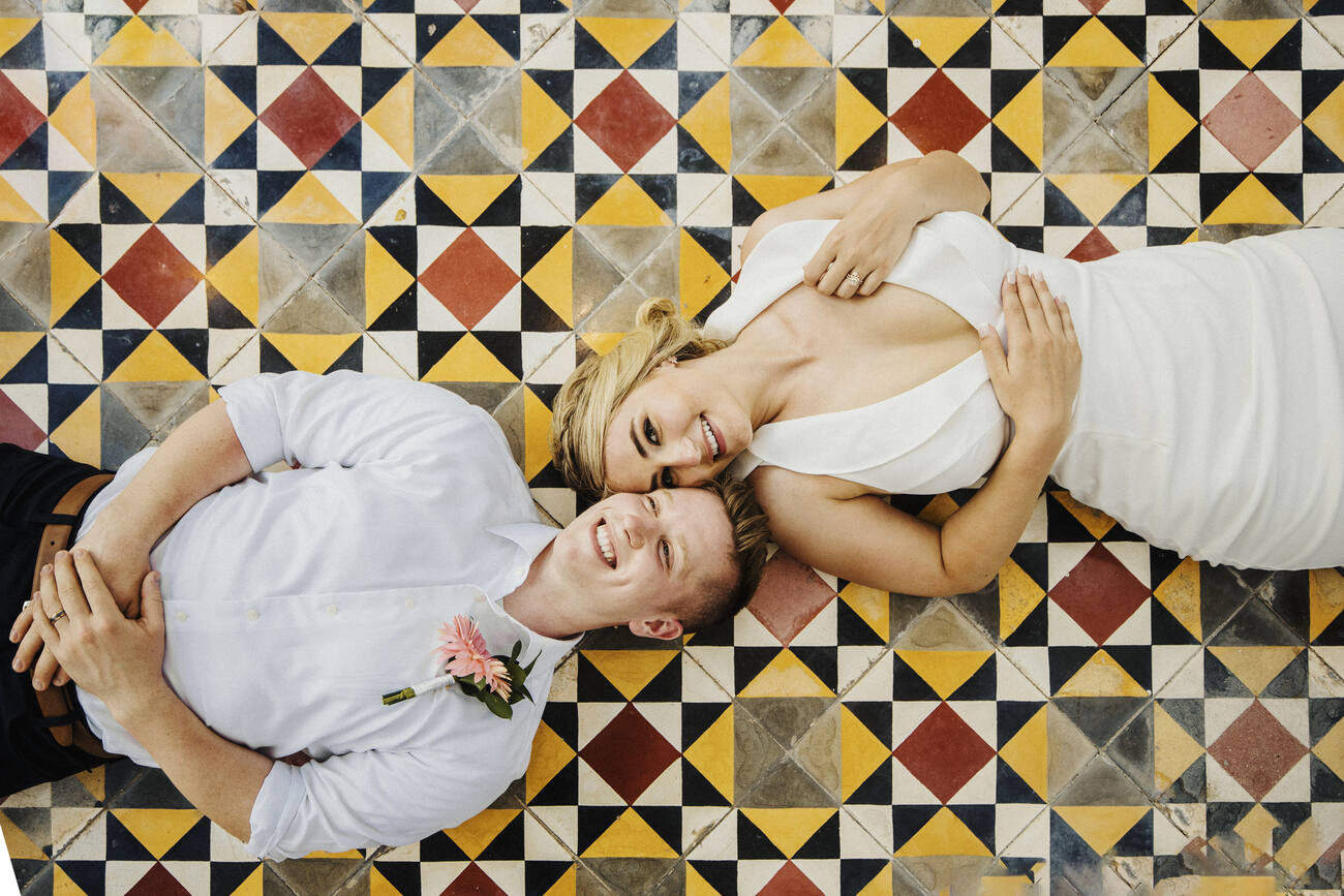 Bride and groom laying on a tile floor
