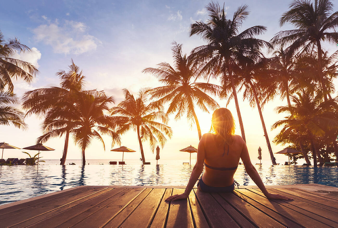 Woman sitting by an infinity pool overlooking the ocean