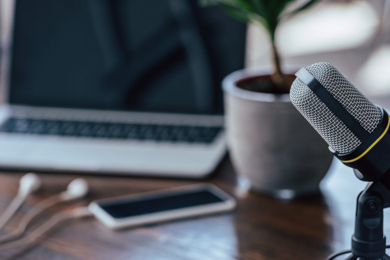 A microphone in front of a laptop on a desk.