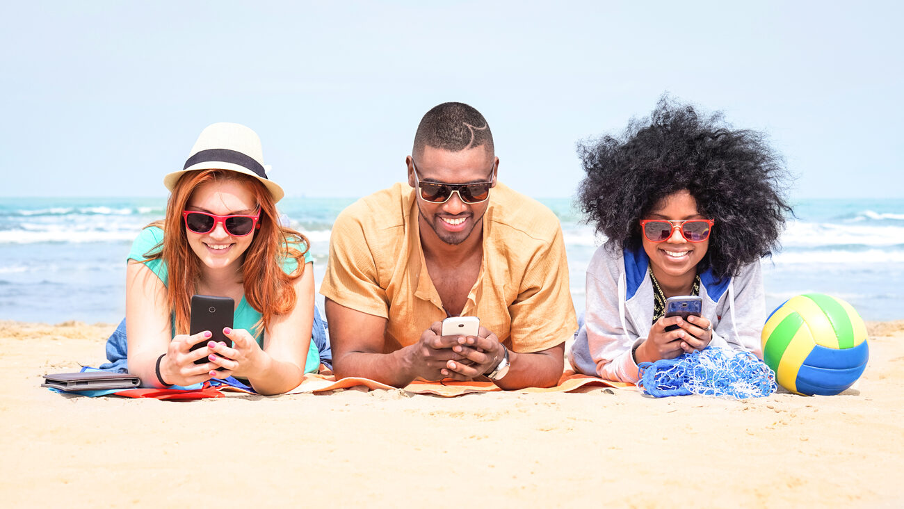 People laying on the beach on their phones