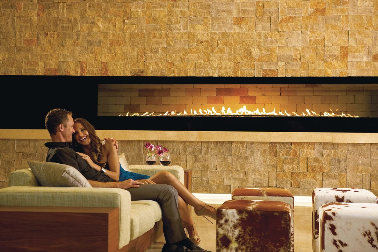 Couple drinking wine by a fireplace