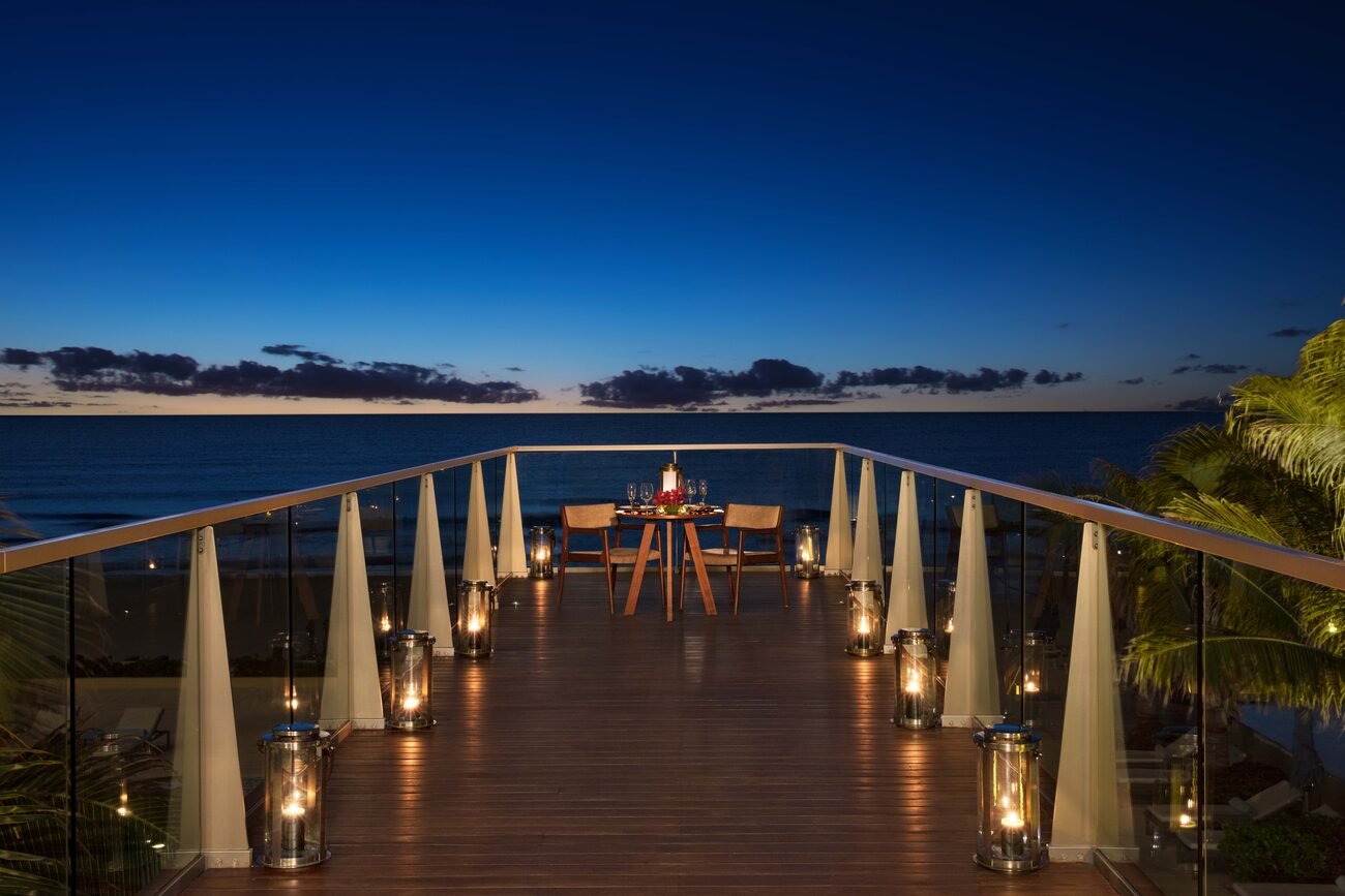 Walkway that ends with a candlelit dinner table overlooking the ocean